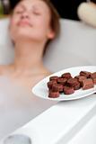 Attractive woman eating chocolate while having a bath 