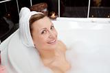 Smiling young woman in a bubble bath 