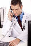 young physician sitting at his desk talking over phone