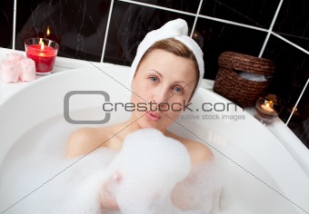 Delighted woman having fun in a bubble bath 