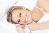 Smiling beautiful woman relaxing on her bed at home