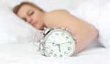 Blond woman holding an alarm clock 