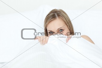 Radiant blond woman hiding in her bed 
