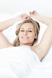 Cheerful blond woman resting lying on a bed