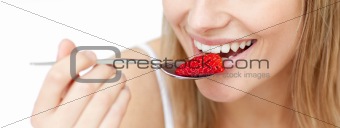 Close-up of a smiling woman eating a strawberry 