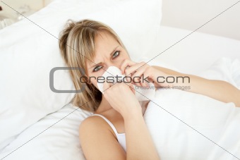 Sick blond woman blowing lying on her bed 