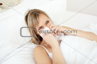 Sick young woman blowing lying on her bed