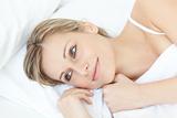 Smiling relaxed woman lying on her bed 