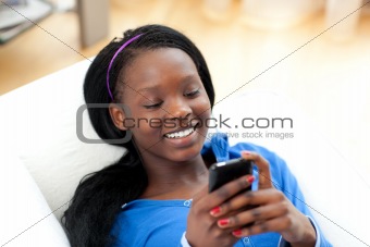 Radiant woman sending a text lying on a sofa