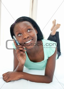 Happy teen girl using a mobile phone lying on her bed