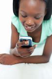 Afro-American teen girl using a mobile phone lying on her bed