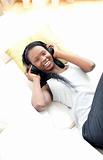 Radiant woman listening music with headphones lying on a sofa