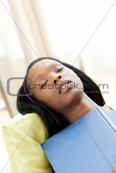 Exhausted teen girl studying lying on a sofa