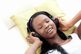 Relaxed woman listening music with headphones lying on a sofa