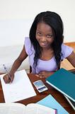Smiling Afro-American teen girl doing her homework 