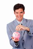 Cheerful businessman saving money in a piggy-bank 