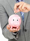 Close-up of a businessman saving money in a piggy-bank