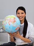 Assertive asian businesswoman holding a globe 