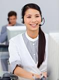 Smiling businesswoman with headset on at a computer 