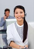 Cheerful young businesswoman with headset on at a computer 