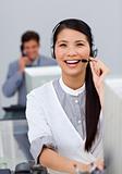 Laughing asian businesswoman with headset on at a computer 