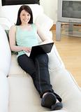 Smiling woman surfing the internet lying on a sofa