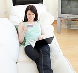 Charming woman shopping on-line lying on a sofa 