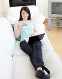 Cheerful woman shopping on-line lying on a sofa 