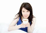 Charming woman drinking a coffee sitting on her bed 