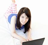 Attrative woman surfing the internet lying on a bed 