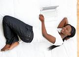 Smiling teen girl using a laptop lying on her bed
