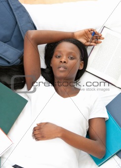 Young student doing her homework lying on a bed 