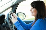 Smiling teen girl using a mobile phone while driving 