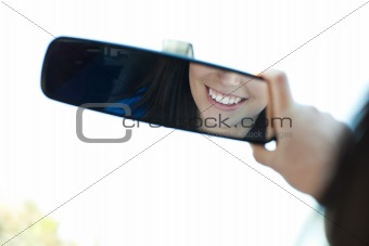 Smiling woman  looking in the rear-view mirror