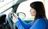 Attractive teen girl using a mobile phone while driving 