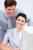Smiling business woman and her colleage working at a computer