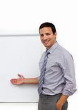 Assertive young businessman pointing at a board 