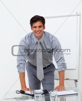 Cheerful businessman leaning on a conference table 