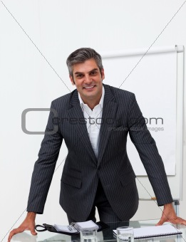 Charming businessman leaning on a conference table 