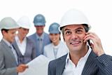 Confident male architect on phone in front of his team