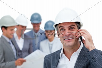 Confident male architect on phone in front of his team