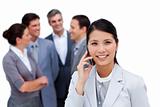 Jolly businesswoman talking on phone in front of her team
