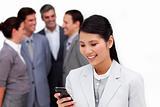 Smiling businesswoman sending a text with a mobile phone with his team