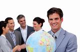 Happy businessman holding a globe in front of his team