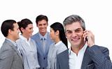 Smiling businessman on phone standing apart from his team