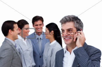 Confident mature manager on phone standig in front of his team