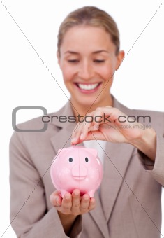 Smiling businesswoman saving money in a piggybank
