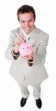 Cheerful businessman saving money in a piggybank 