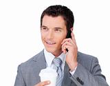 Smiling businessman on phone holding a drinking cup 