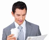 Businessman holding a drinking cup and reading a newspaper